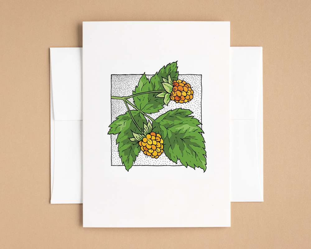 A vertical white card depicts two yellow-orange berries and green leaves. The card sits on top of a white envelope, which lies on top of a brown backdrop.